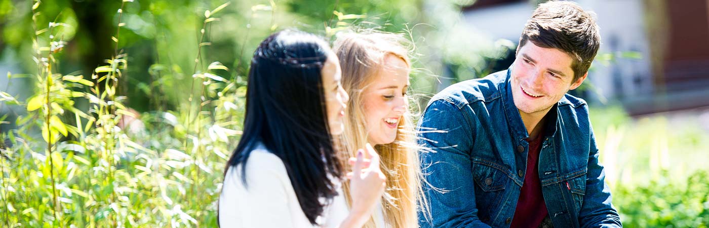 Three students smiling outside.